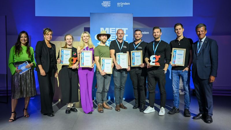 Die teilnehmenden Start-ups am Finale der Roadshow (v. l.: RecyCoal, BETTER CAKEZ, keep it grün, PALPRINT, vGreens, Stallgrün) mit Moderatorin Sophia Tran, Wirtschaftsministerin Mona Neubaur und dem Vorstandsvorsitzenden der NRW.Bank.