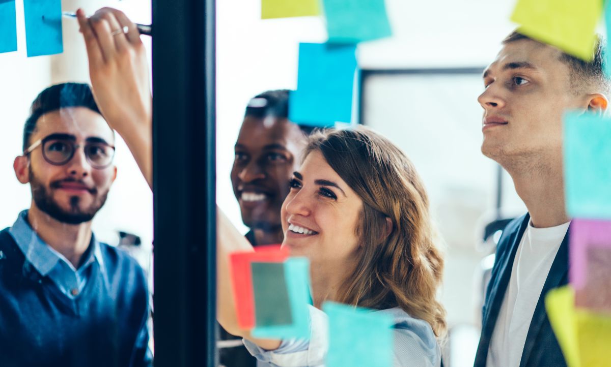 Vier junge Menschen stehen vor einem mit Post-it beklebtem Fenster